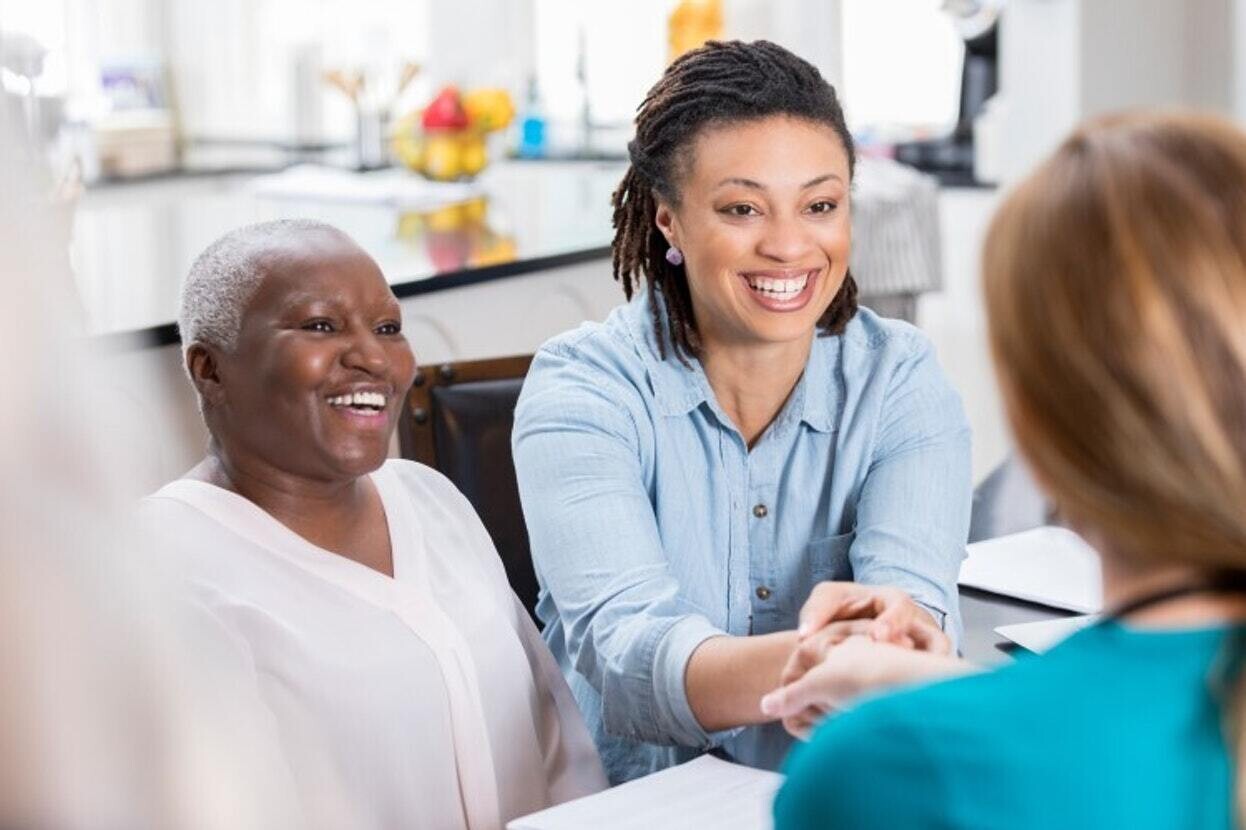 Mother and daughter sitting at a desk meeting with female doctor